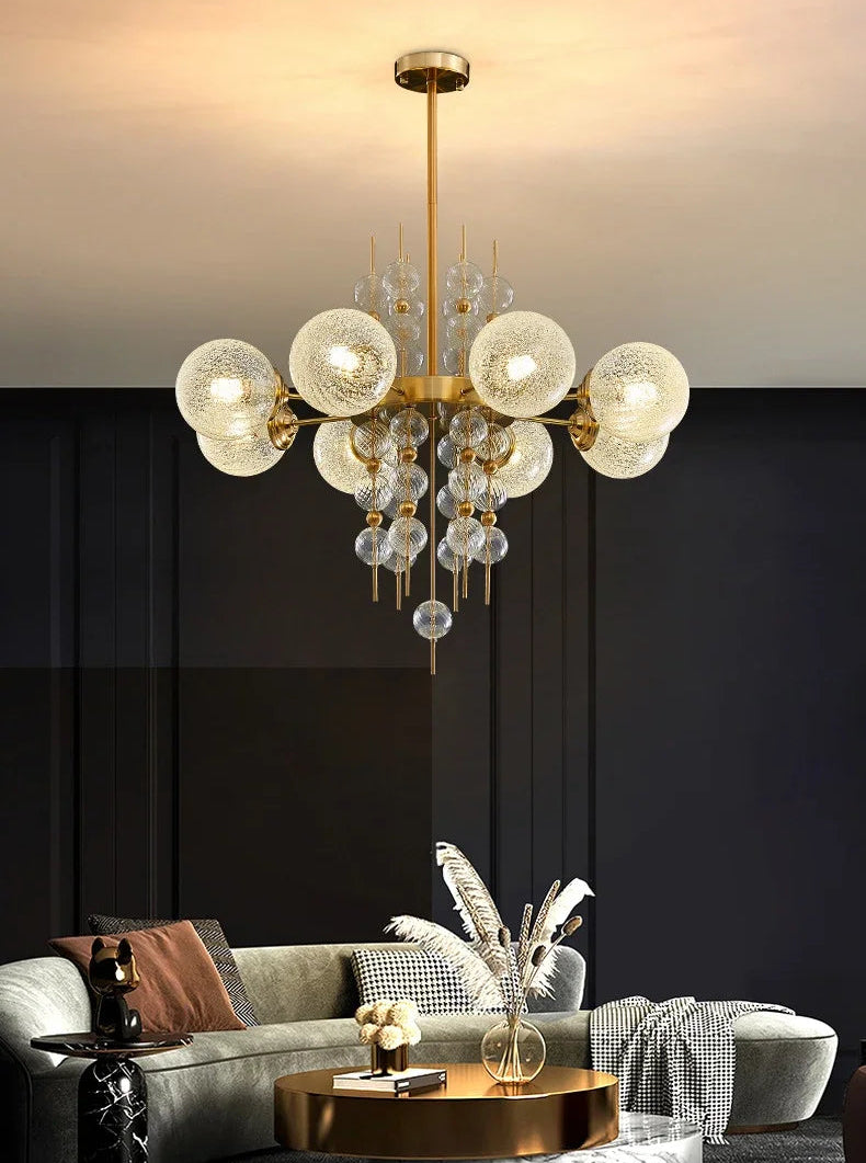 Modern chandelier hanging above a living room with a dark wall and gray sofa.