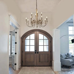 Candle-style chandelier with distressed wood finish installed in a home entryway above a large wooden door