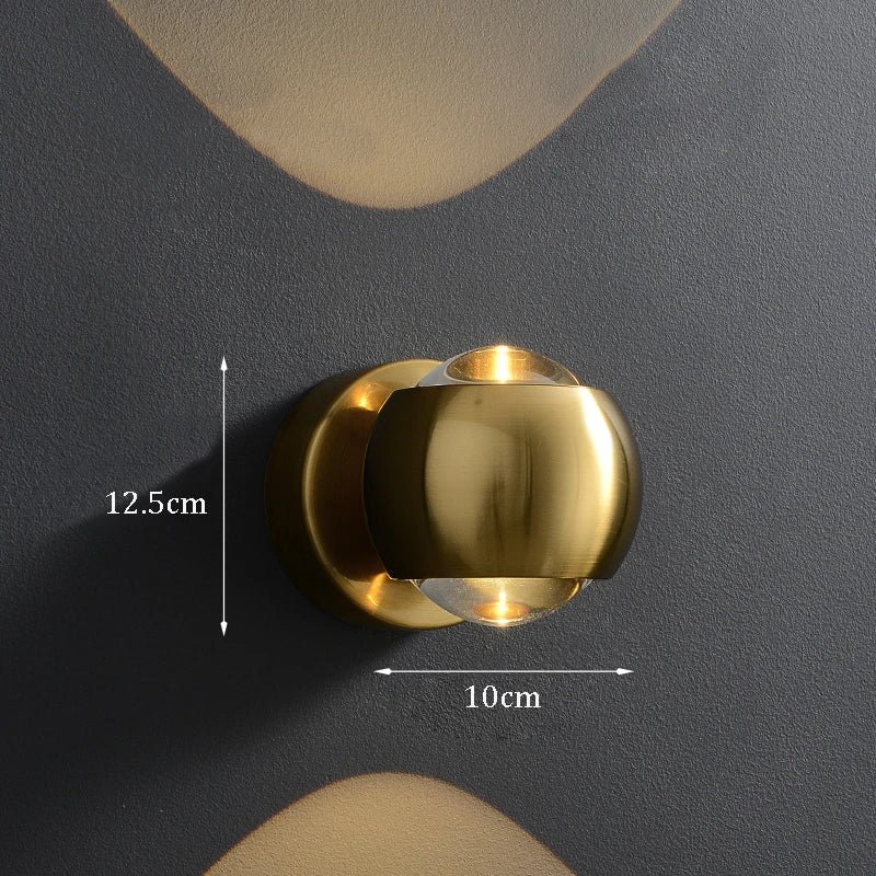Gold wall sconce on a dark gray wall with measurements indicated.