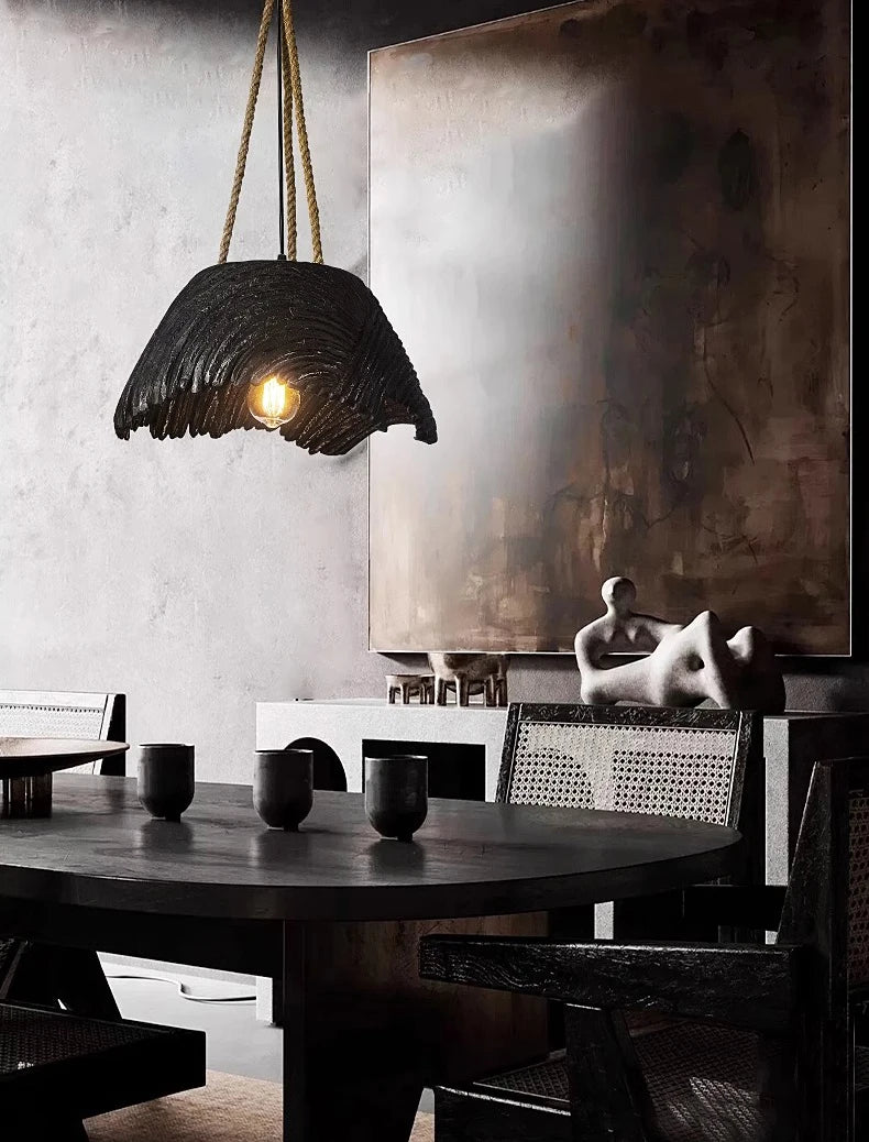 Dining room with a dark pendant light, round table, and abstract painting on the wall.