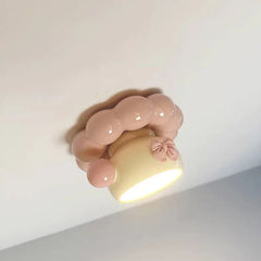 Close-up angled view of the pink ceramic coffee cup ceiling light, showing the detail of the bow and the soft pink trim.