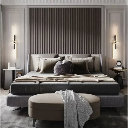 Two modern geometric wall sconces with gold finishes flanking a bed, illuminating the bedside area.