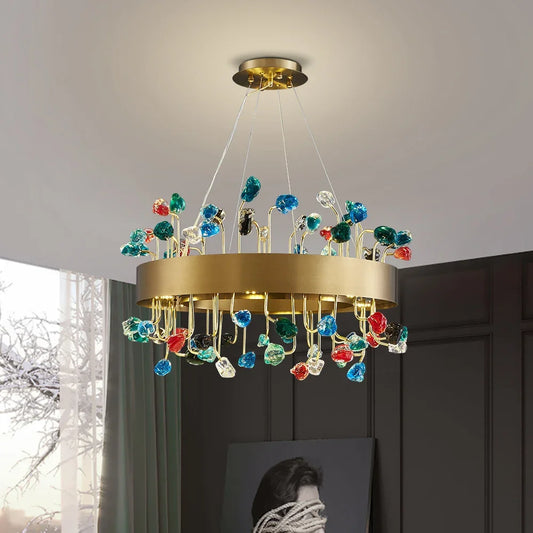 A round gold chandelier with colorful crystal accents hanging from the ceiling in a room.