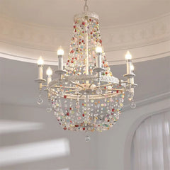 Close-up of a white multi-arm chandelier adorned with colorful beads and crystal drops, illuminated.
