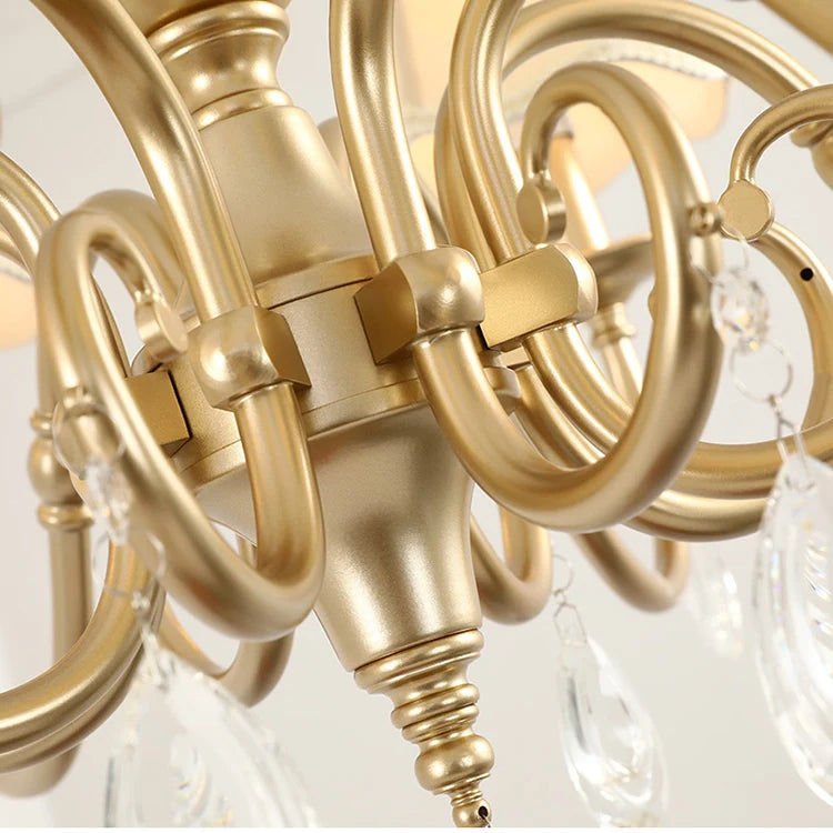 Close-up of a gold chandelier with clear glass elements on a light background