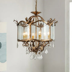 A gold candelabra pendant light with a glass shade and crystal droplets, suspended in a room with soft lighting and modern decor.
