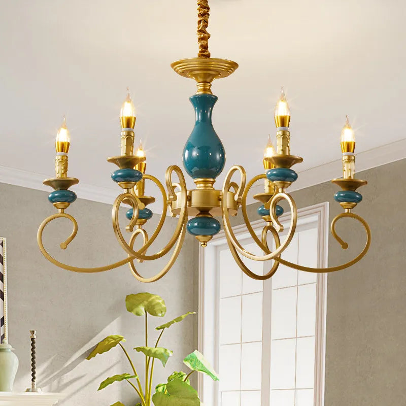 A wider view of the gold candelabra chandelier with teal ceramic accents illuminating a room.