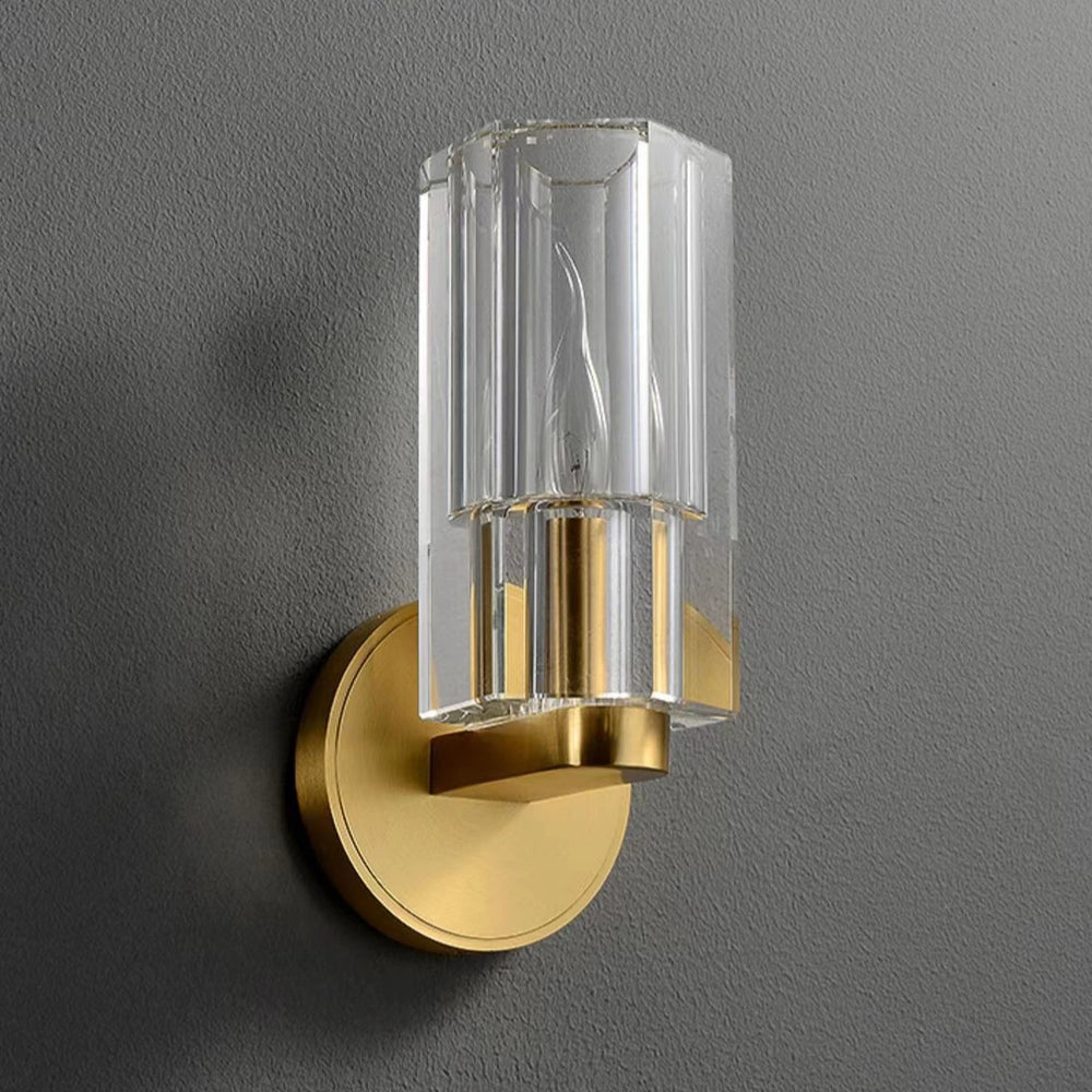 Gold wall sconce with clear glass on a gray wall