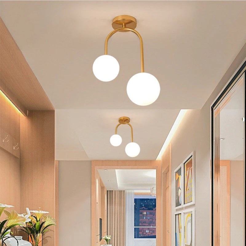 A hallway with multiple gold arch globe semi-flush ceiling lights installed, casting a warm glow.