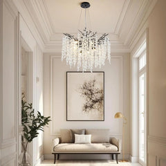 A multi-tiered, curved chandelier with crystal accents, suspended in a hallway above a sofa and artwork.