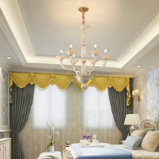 A champagne ceramic and glass chandelier installed in a bedroom with yellow drapes and grey curtains.