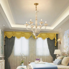 A champagne ceramic and glass chandelier installed in a bedroom with yellow drapes and grey curtains.