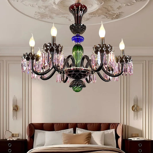 Close-up of a multi-colored crystal chandelier with candelabra-style arms, illuminating a bedroom.