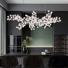 A medium shot of a dining room with a gold grapes bunch chandelier hanging above a table.