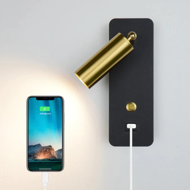A smartphone being charged via the USB port on a black wall sconce with a gold spotlight.