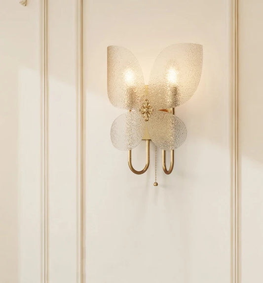 Close-up of the gold butterfly wall sconce, highlighting the textured frosted glass wings and central floral accent.