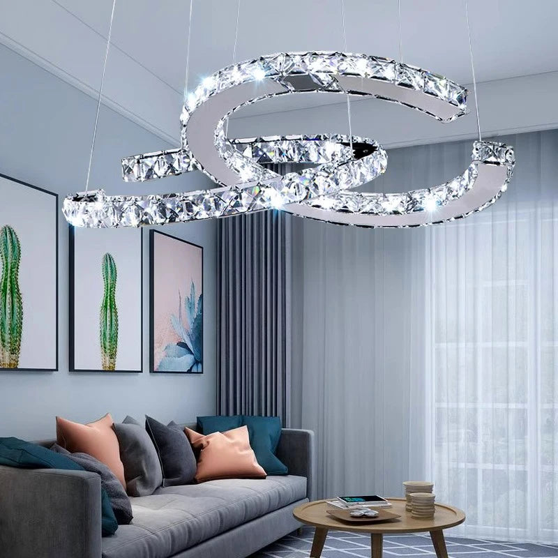 Modern chandelier hanging in a living room with a gray sofa and decorative pillows.