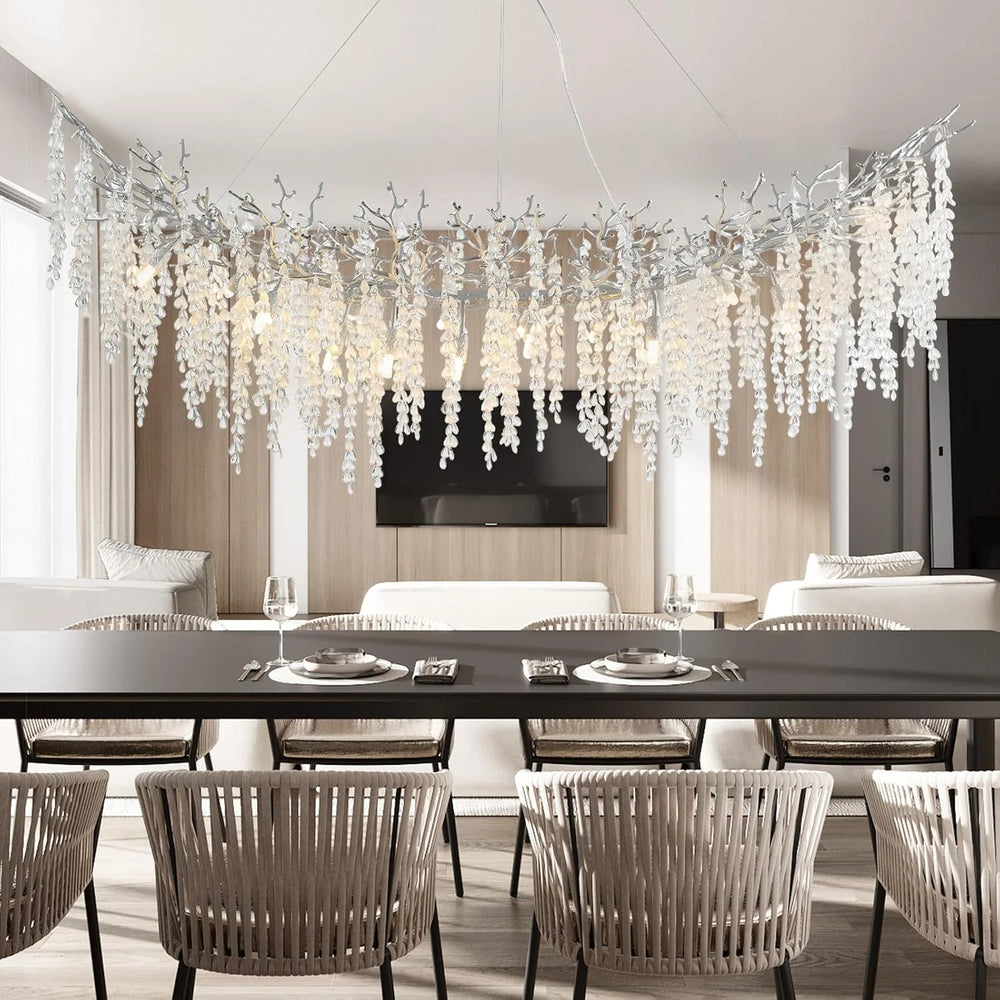 Curved chandelier with numerous clear crystal teardrops hanging from dark branches, suspended over a dining table.
