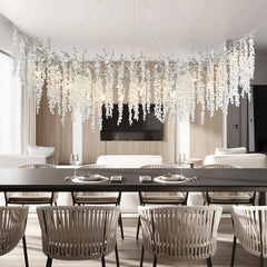 Curved chandelier with numerous clear crystal teardrops hanging from dark branches, suspended over a dining table.