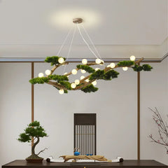 Close-up of a branch-shaped chandelier featuring numerous small LED lights and artificial greenery, showcasing the wood texture and the suspension wires against a white ceiling.