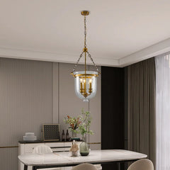 Polished copper and clear glass drum pendant light in a dining room setting