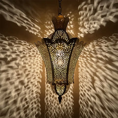 A close-up view of a gold hollow carved floral pendant light with internal light source.