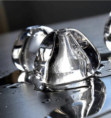 Close-up of a clear crystal ball pendant light with water droplets on a reflective surface.