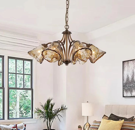 Bedroom with a copper floral chandelier featuring smoked glass shades hanging above a bed.