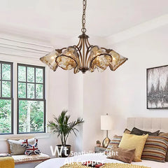 Bedroom with a copper floral chandelier featuring smoked glass shades hanging above a bed.