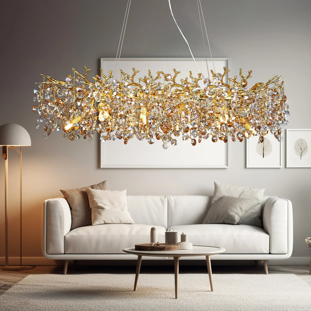 Gold crystal chandelier with a branch-like design and clear faceted crystals hanging above a white sofa in a living room setting.