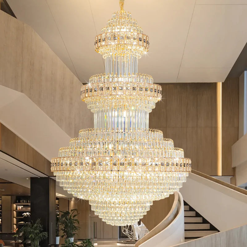 A large, multi-tiered crystal chandelier with a gold frame, installed in a high-ceiling entryway.