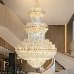 A large, multi-tiered crystal chandelier with a gold frame, installed in a high-ceiling entryway.
