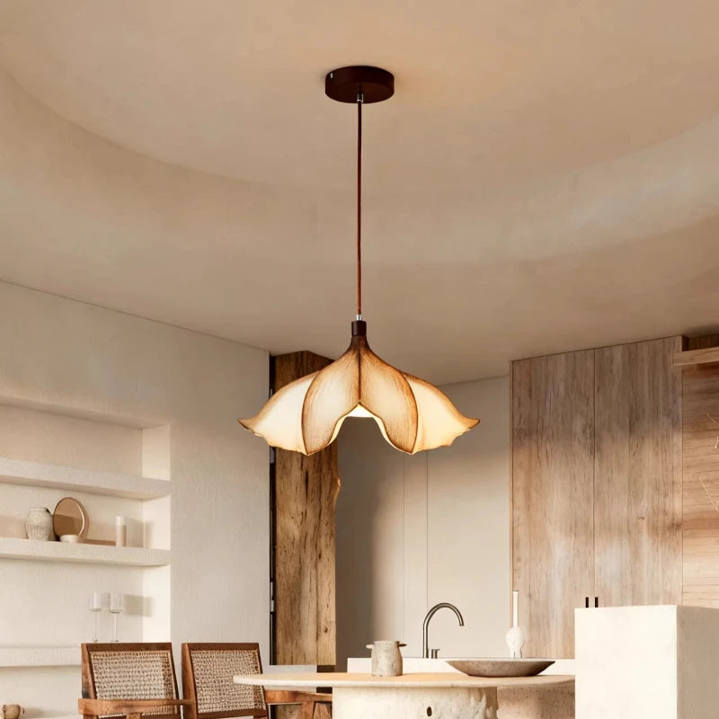 Beige floral pendant light hanging from a dark brown cord and ceiling canopy in a bright, modern kitchen or dining area with wooden accents.