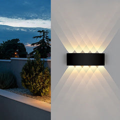 Black geometric wall sconce mounted on a textured wall, creating a dramatic light effect.