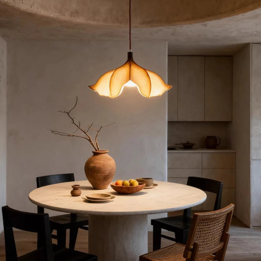 Beige floral pendant light hanging over a marble-top dining table with a vase and fruit bowl, in a modern interior setting.