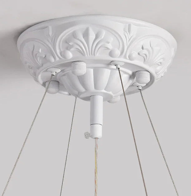 Decorative white ceiling rose with three light fixtures on a plain background