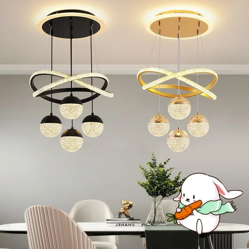 Two modern pendant lights in black and gold hanging above a dining table with decorative elements.