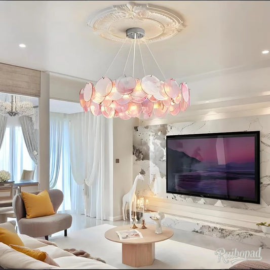 A living room scene with a pink crystal chandelier illuminating the space above a sofa and coffee table.