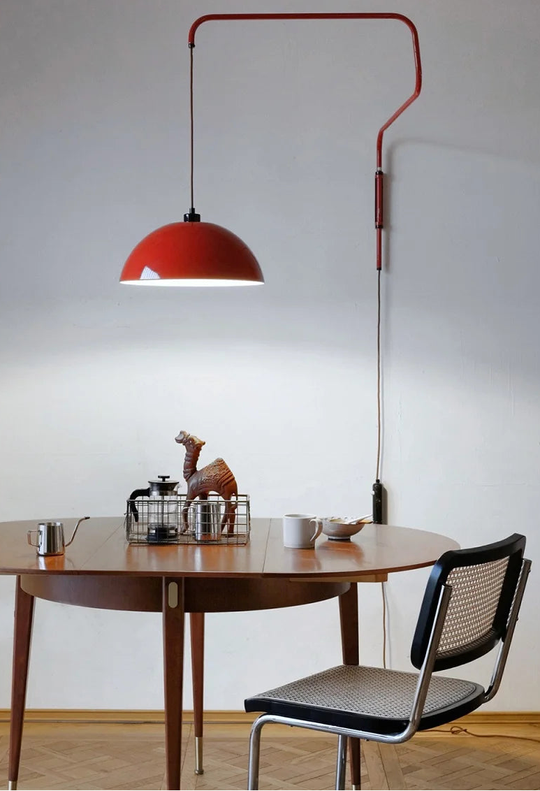 Dining area with a red pendant light, wooden table, and black chair.