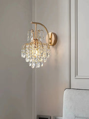 Close-up of a gold wall sconce with clear teardrop crystals reflecting light.