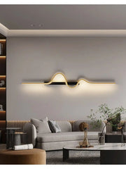 A long, horizontal gold wave wall fixture mounted above a sofa in a living room.
