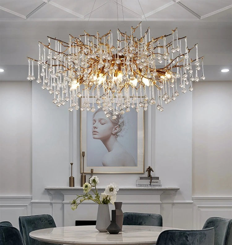 Dining room with a large chandelier, round table, and gray chairs.