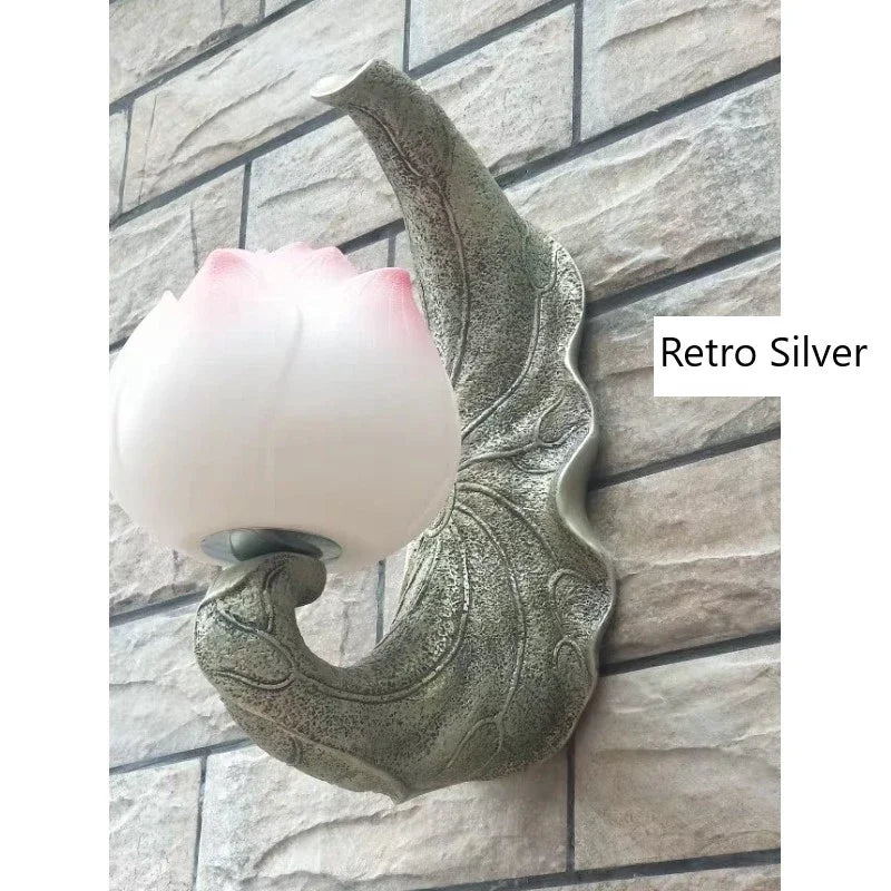 Decorative wall light fixture with pink lampshade on a stone wall background