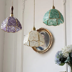 Three decorative pendant lights with colourful glass shades hanging against a white wall. Modern  glass mosaic hanging lamp for kitchen, dining, or living