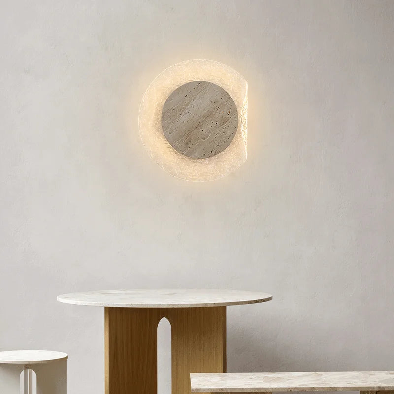 Round wall light fixture on a plain wall with a table in the foreground