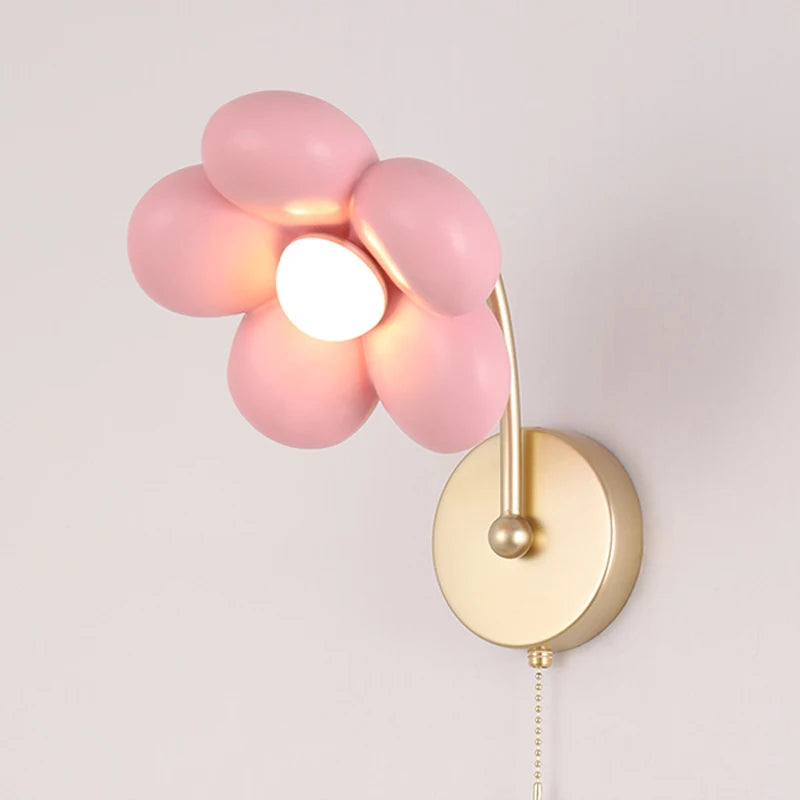 Wall-mounted lamp with pink flower-shaped glass shade on a white background