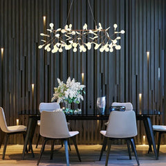 Modern dining room with a chandelier, table, and chairs against a dark paneled wall.