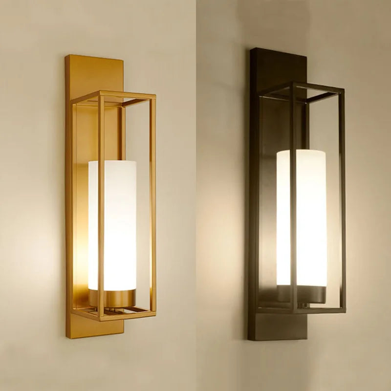 Two wall sconces, one gold and one bronze, on a neutral wall.