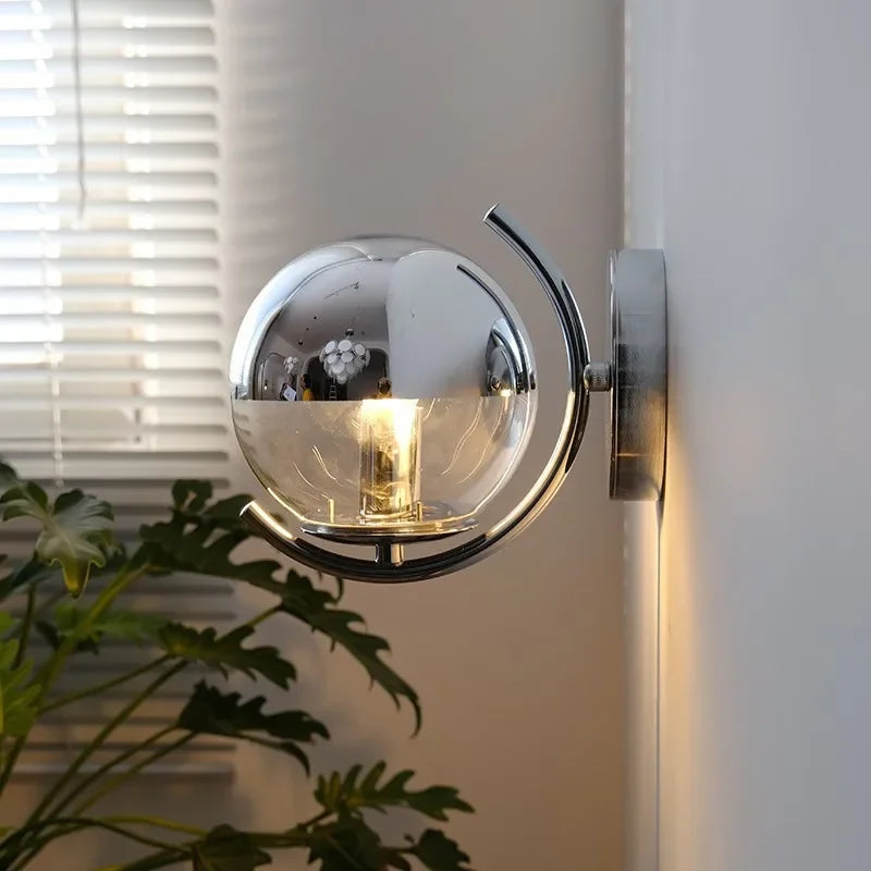 Modern wall-mounted light fixture on a white wall with a plant in the foreground.