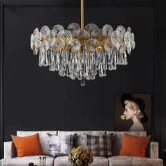 Luxury chandelier hanging above a sofa with decorative pillows against a dark wall.